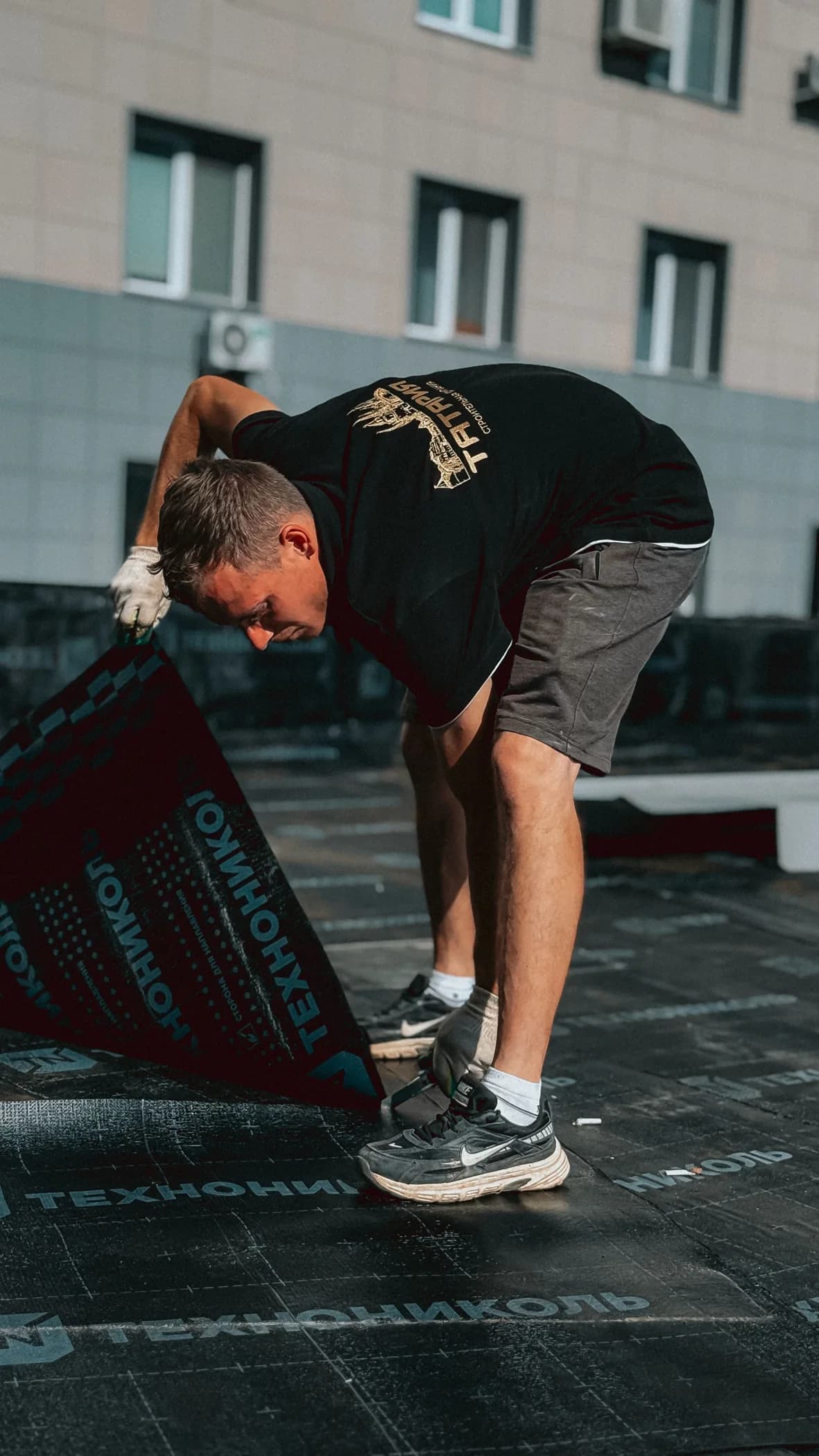Artisan déroulant une membrane d’étanchéité sur une toiture
