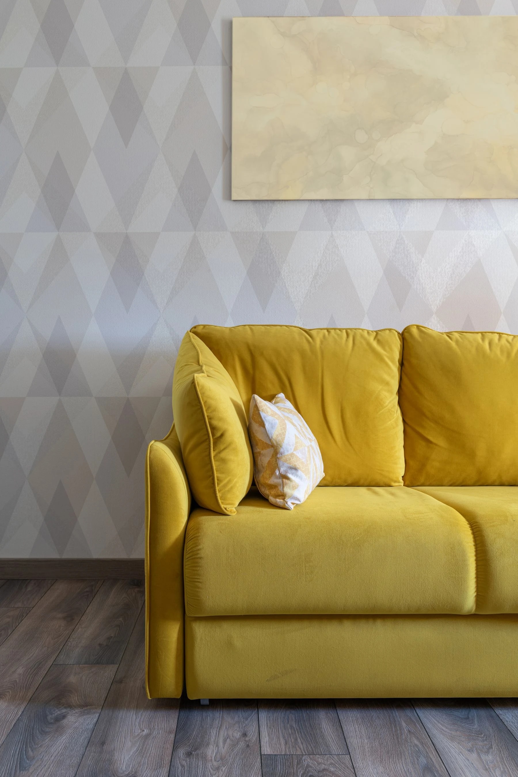 Salon avec papier peint géométrique et canapé jaune
