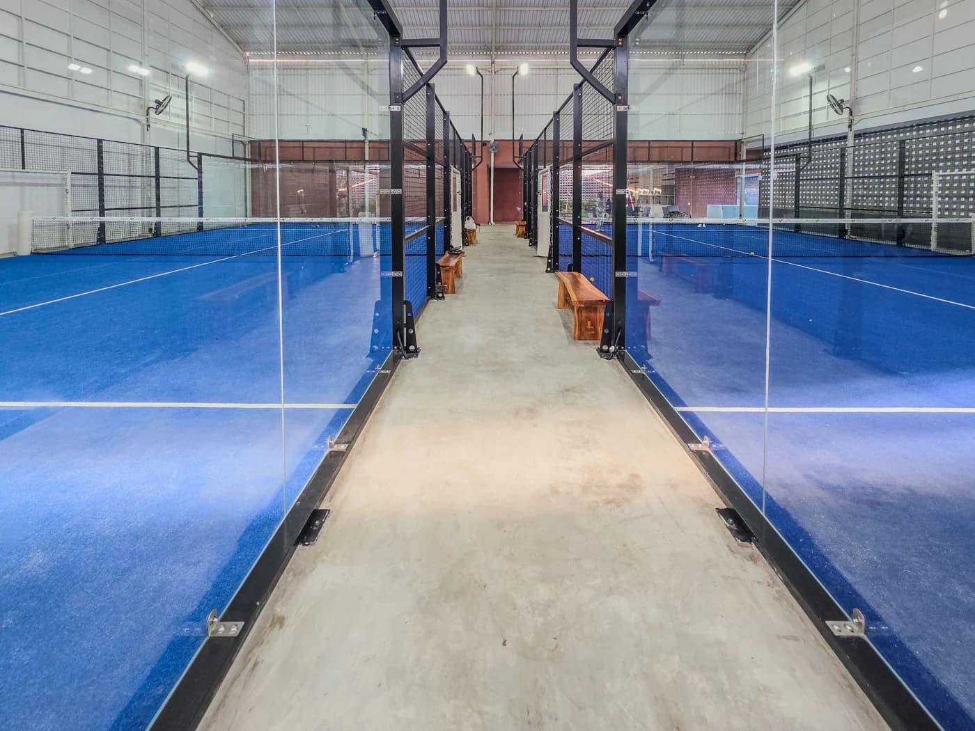 Plusieurs terrains de padel avec une circulation commune dans un club couvert