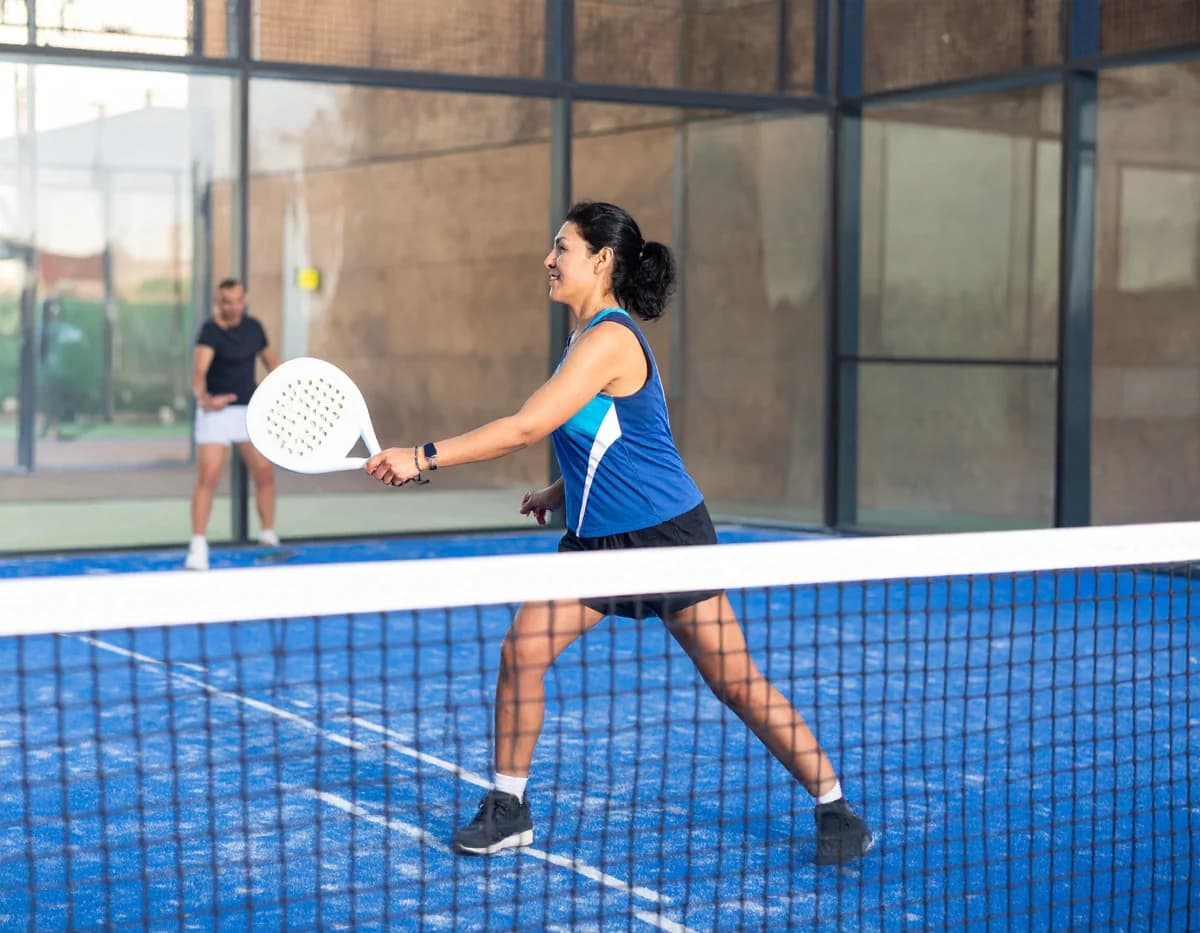 Joueuse en action sur un court de padel vitré